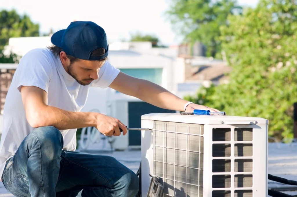 A technician is repairing an air conditioning unit, focused on ensuring optimal performance and efficiency.