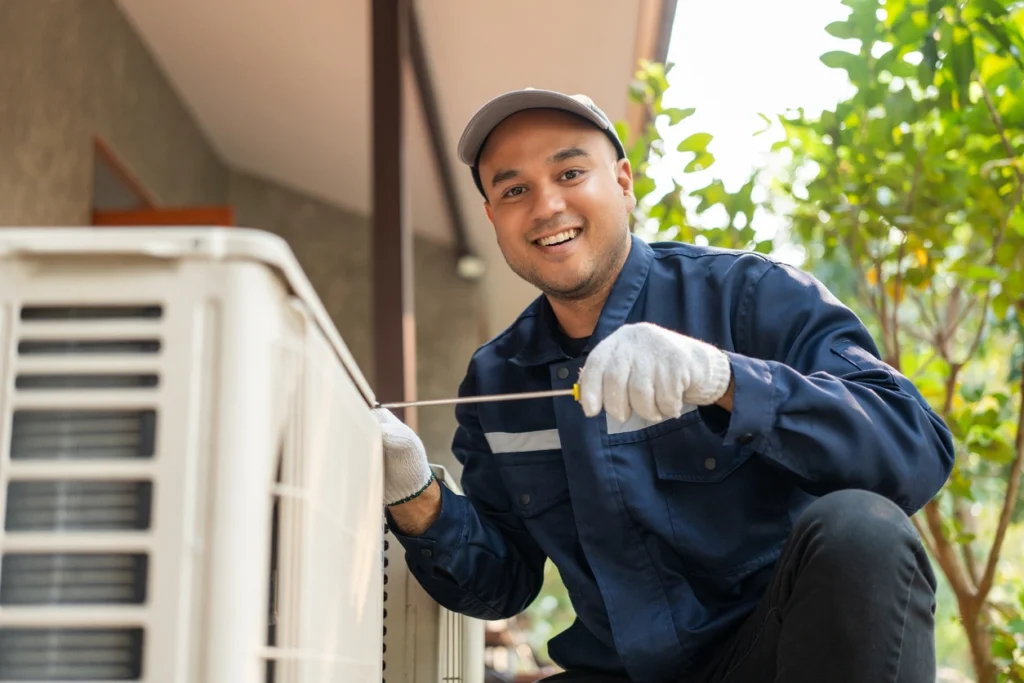 A man wearing a blue shirt and white gloves repairs an air conditioner, demonstrating technical skill and attention to detail.